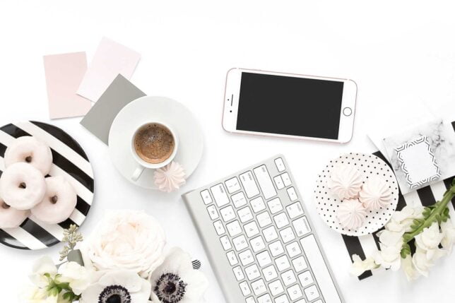 Table assortment with coffee, sweets and tech.